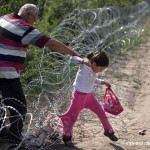 Flüchtlinge überwinden am 3. September 2015 einen Stacheldrahtzaun an der serbisch-ungarischen Grenze in Röszke. Die Flüchtlinge klettern über den inzwischen 175 Kilometer langen Zaun an der Grenze zwischen Serbien und Ungarn.
